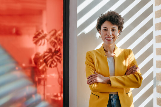 Smiling businesswoman in yellow blazer standing in a modern office