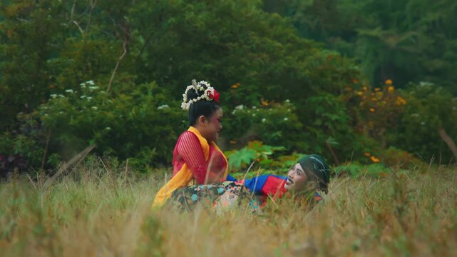 Happy and Playful Moment Between Two Indonesian Dancers in Grass
