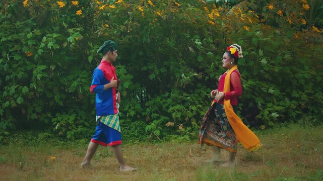 Male and Female Indonesian Dancers Approaching Each Other in an Outdoor Scene