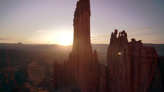 Stunning aerial footage of a person walking a slackline between two sandstone towers at sunset