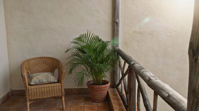 Inviting Terracotta-Tiled Balcony with a Comfortable Wicker Chair, Lush Potted Palm Plant,