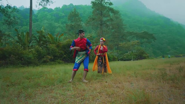 Traditional Indonesian Dancer in Low Pose with Partner Watching in Background