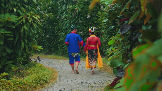 Romantic Walk of Traditional Indonesian Dancers Hand-in-Hand on Path