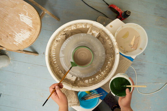 Creative process of hand painting a ceramic bowl with dark green underglaze.