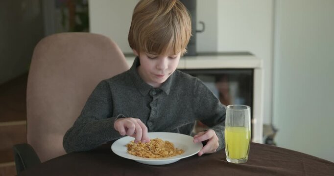 Kid Boy Eats Corn Flakes Meal in Kitchen. 4K 10-bit