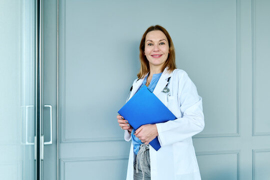 Confident doctor holding folder at clinic looking at camera