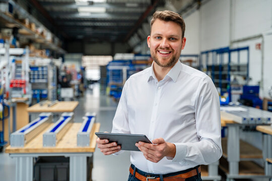 Smiling manager with a tablet in a factory production hall