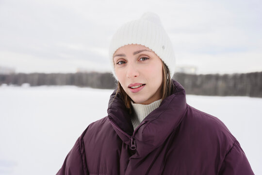 Portrait of a woman in the snow wearing warm winter coat and knit hat
