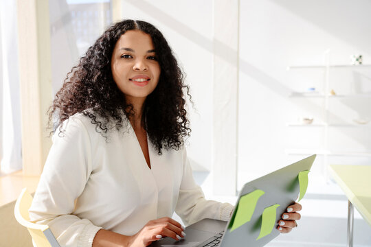Smiling freelancer using laptop with sticky notes indoors