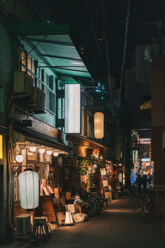 Illuminated izakaya lanterns in a narrow night alley in Osaka