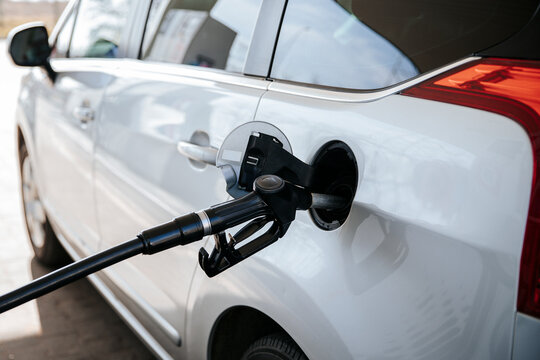 Black fuel nozzle inserted into white car at a gas station