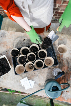 Filling eco-friendly pot with soil using trowel for spring planting