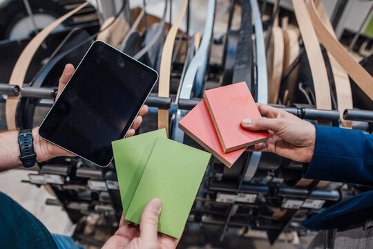 Colleagues with wooden pieces and tablet PC in industry