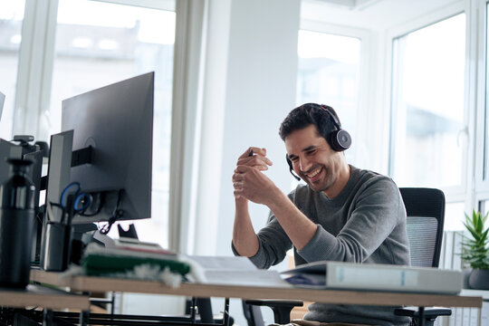 Cheerful mature businessman wearing headset and talking in office
