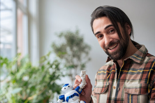Businessman waving hand with toy robot at office
