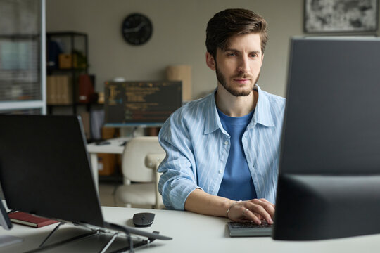 Focused programmer coding on computer at desk