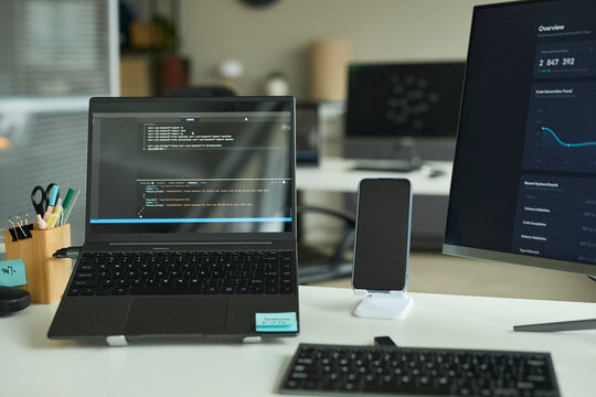 Modern office desk with a laptop showing code and monitor