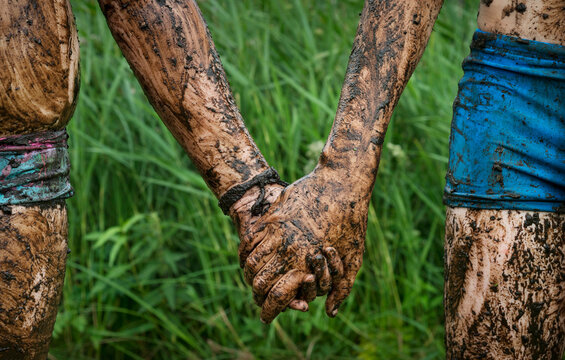 Muddy brother and sister holding hands outdoors