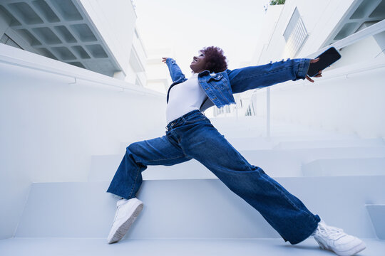 Energetic woman dancing on white urban stairs outdoors