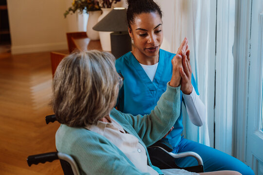 Caregiver giving compassionate assistance to woman in wheelchair at home