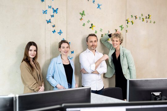 Colleagues standing in front of wall with butterflies stickers at office