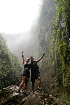 Happy couple celebrating on rock at Tumpak Sewu Waterfall Java