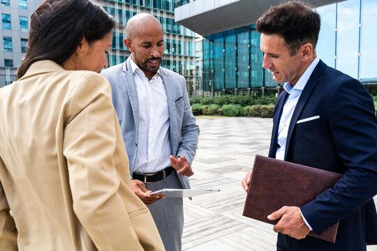 Business team discussing project on tablet in financial district
