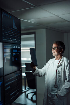 Doctor with tablet analyzing data in dark hospital