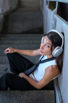 Music lover sitting on urban staircase with headphone and tie
