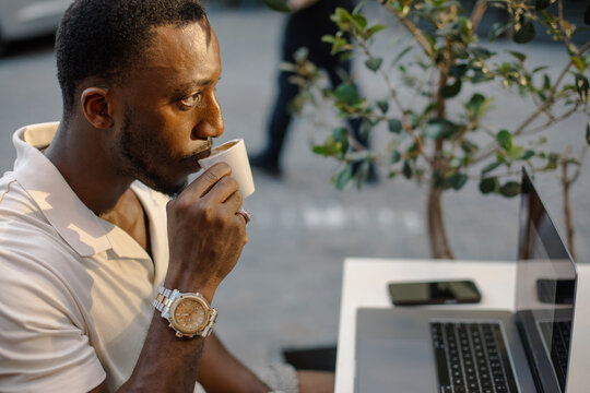 Freelancer drinking coffee during remote work break at outdoor cafe