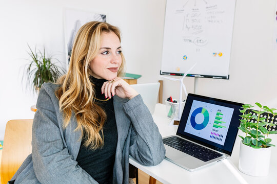 Smiling businesswoman sitting with laptop at desk