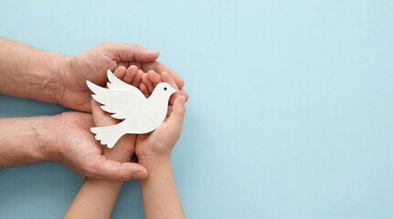 White paper dove held in adult and child hands, peace symbol for international harmony, hope and freedom concept on blue background