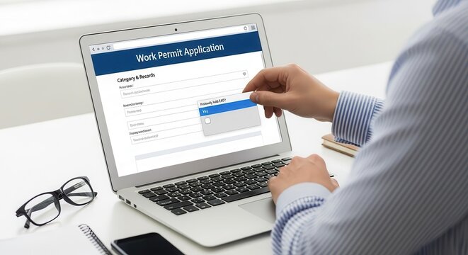 Man Filling Out Online Work Permit Application Form on Laptop Screen at Desk in Office Environment