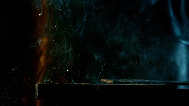 Cinematic close-up of blacksmith forging glowing hot iron on anvil with sparks flying. Shot in dramatic lighting on dark background with high-speed camera at 1000fps. Speed ramp.