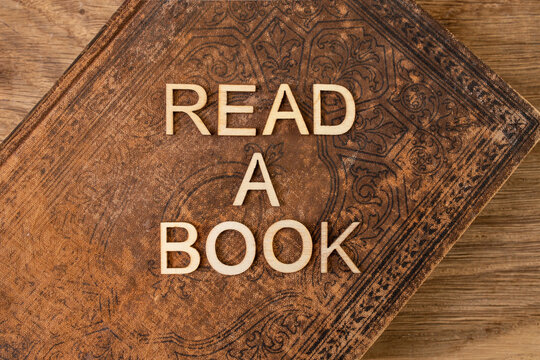 Read a book words written with wooden letters on a vintage hardcover book texture