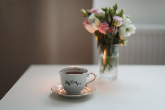 Home cozy still life scene. Table composition with cup of coffee, tea and flowers. Beautiful floral bouquet with roses