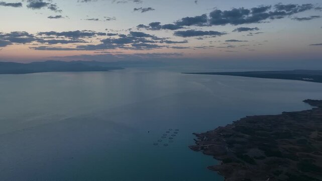 Scenic sunset or sunrise over Sevan lake popular holiday destination in Armenia, Caucasus, West Asia. Daytime Timelapse of moving white, grey clouds over lake Sevan on background hills