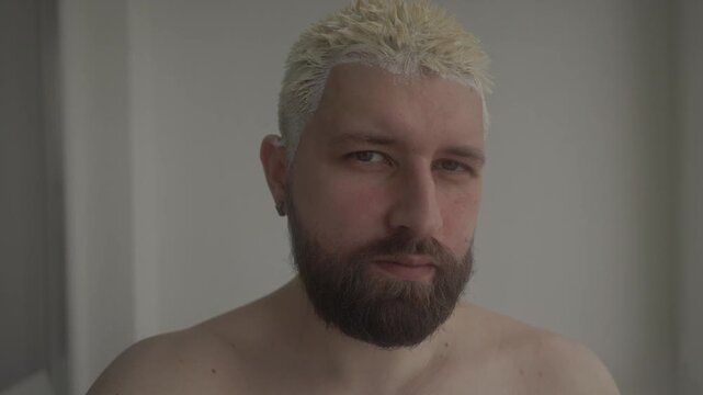 A young man takes a selfie while dyeing his hair 