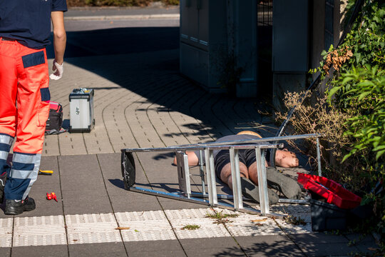 Man lying on ground after electric shock accident with ladder and cable
