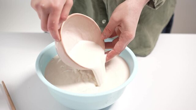 Artisan handles an unglazed clay vessel during the manual glazing process. Artisan Dipping Ceramic Bowl into Glaze Basin 4K Video Slow Motion