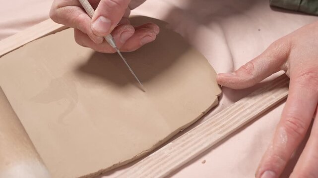 Artist Rolling Clay Slab with Rolling Pin 4K Video Slow Motion. Artist uses a wooden rolling pin to flatten raw earthenware clay into a uniform slab for ceramic artwork