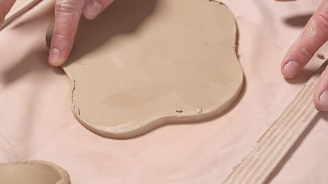 Artisan Smoothing Clay Edges with Finger 4k slow motion video. Hand smoothing the raw edges of a freshly cut clay artwork with a finger in a studio workspace
