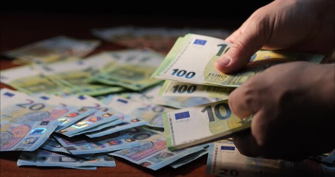 Counting money and income. Flipping through euro banknotes in a bundle with hands.