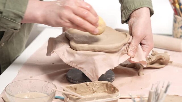 Artisan Refining Clay Edges with a Sponge 4k video slow motion. Close-up of pottery artwork refinement. Artisan hand gently wipes the border of an earthenware slab to remove imperfections
