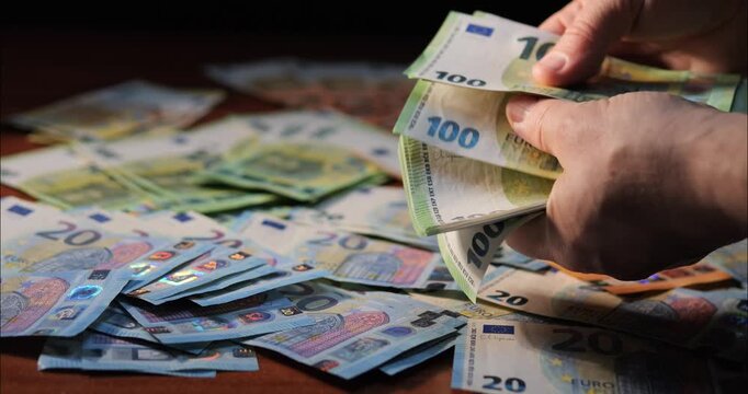Counting money and income. Flipping through euro banknotes in a bundle with hands.