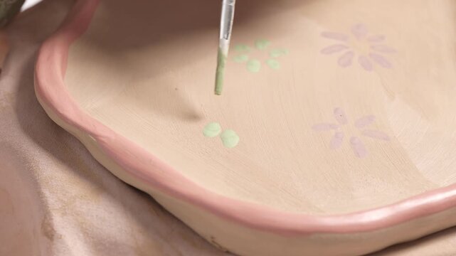 Artist Painting Flowers on Ceramic Plate 4K Video Slow Motion. Artist paints a detailed botanical pattern for a 4k video slow motion ceramic artwork project