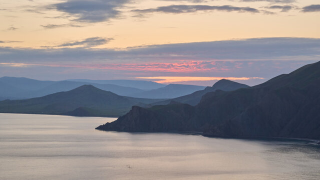 Mountain coastline at sunset over calm sea