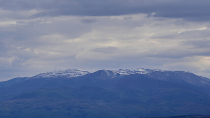 Obraz premium Snow covered mountain ridge under cloudy sky