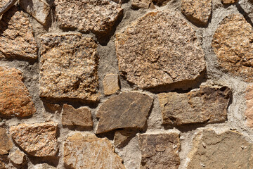 Fototapeta premium Close-up of a rustic stone wall with irregular shapes and natural textures, modern wallpaper, background or web banner