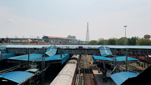Aerial View of a Busy Train Station with Distinctive Blue Canopies, Railway Tracks, and Surrounding Structures Under a Clear Sky on a Bright Day